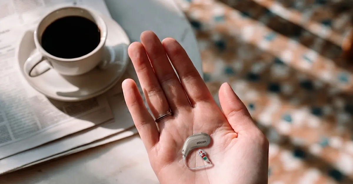 Oticon Reveal hearing aid resting in the palm of a hand